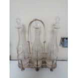 A silver plated three bottle Tantalus on raised feet with three glass decanters