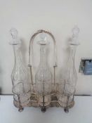 A silver plated three bottle Tantalus on raised feet with three glass decanters