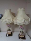 A pair of hand painted porcelain table lamps on brass bases with tasselled shades