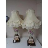 A pair of hand painted porcelain table lamps on brass bases with tasselled shades