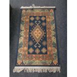 A machine made fringed hearth rug on blue ground. 132 cm x 75 cm.