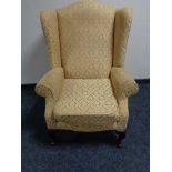 A wing backed armchair by Jade upholstered in golden fabric