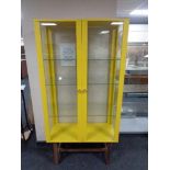 A contemporary double door display cabinet on raised legs