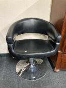 A black leather hydraulic hair dresser's chair