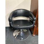 A black leather hydraulic hair dresser's chair