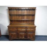 A heavy oak kitchen dresser fitted with three drawers and carved panel doors 186 cm height,