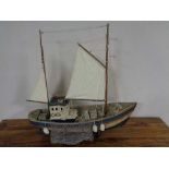 A wooden model of a fishing trawler on wooden stand