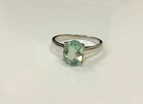 A silver dress ring set with a pale green stone,