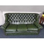 A green buttoned leather wing backed settee