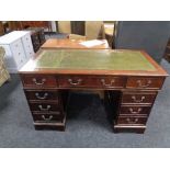 A mahogany twin pedestal writing desk fitted with nine drawers with green tooled leather top.