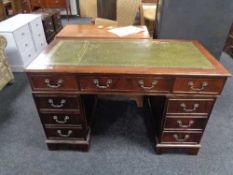 A mahogany twin pedestal writing desk fitted with nine drawers with green tooled leather top.