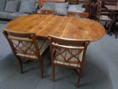 An inlaid yewwood oval dining table together with four chairs