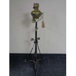 An antique wrought iron rise and fall standard lamp with brass oil lamp