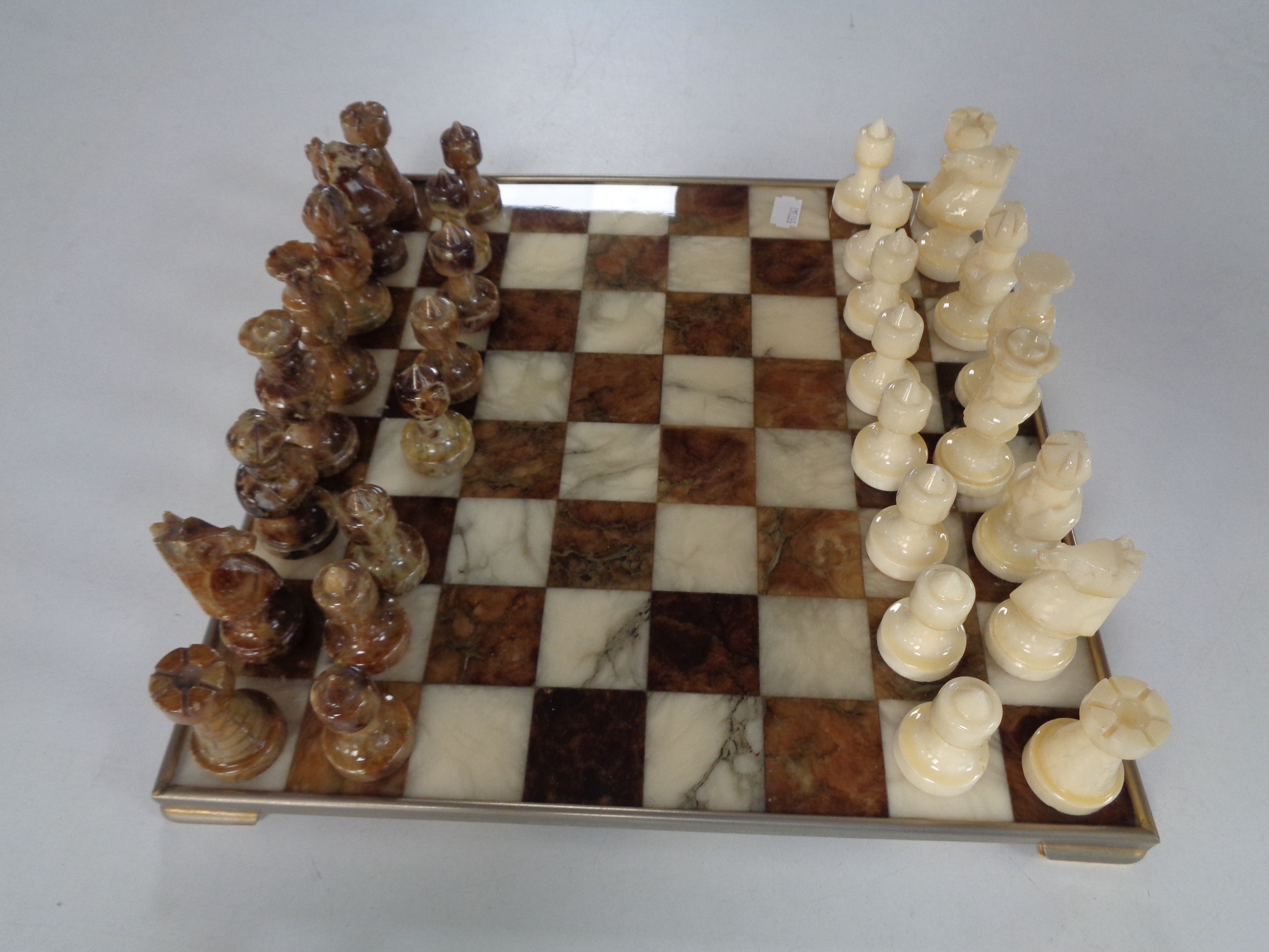 A metal and marble chess board with marble pieces.