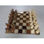 A metal and marble chess board with marble pieces.