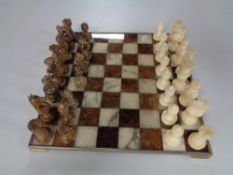 A metal and marble chess board with marble pieces.