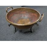 A copper Art Nouveau twin handled bowl on raised cast iron feet, diameter 47 cm.
