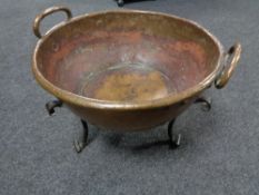 A copper Art Nouveau twin handled bowl on raised cast iron feet, diameter 47 cm.