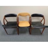 A pair of mid century Danish teak armchairs upholstered in black vinyl together with one other