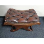 A brown buttoned leather upholstered footstool on X-frame support