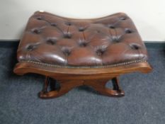 A brown buttoned leather upholstered footstool on X-frame support