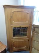 A blond oak triple door corner cabinet