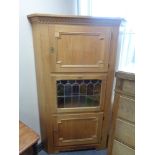 A blond oak triple door corner cabinet