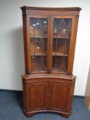 A mahogany Regency style double concave corner cabinet with glazed doors above and panelled doors