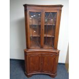 A mahogany Regency style double concave corner cabinet with glazed doors above and panelled doors