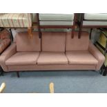 A mid century three seater settee in pink fabric