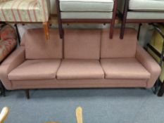 A mid century three seater settee in pink fabric
