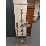An Indian brass standard lamp together with two similar floor standing candlesticks