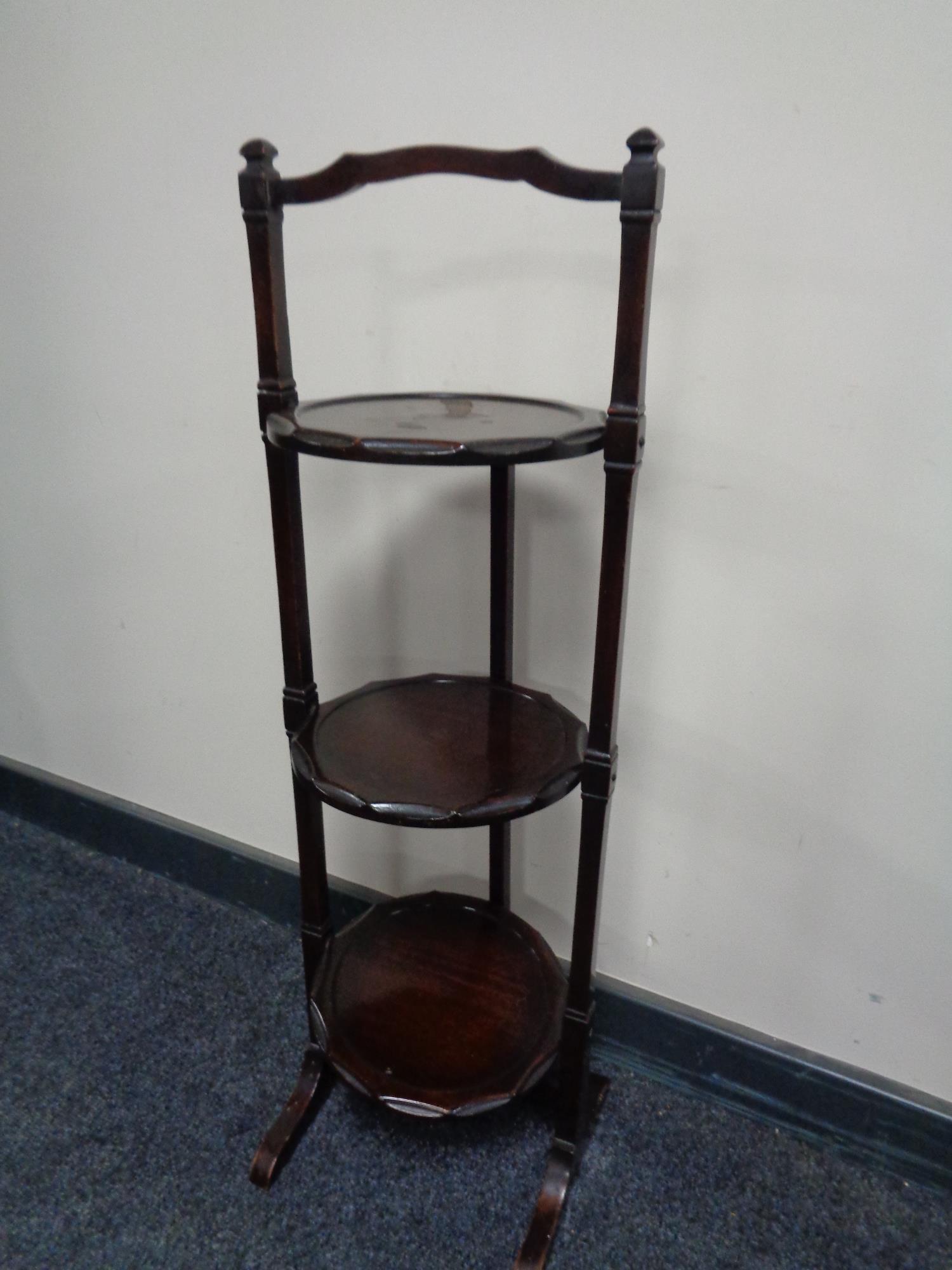 A mahogany three tier folding cake stand