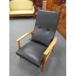 A mid century Danish teak framed adjustable armchair upholstered in black vinyl