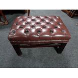 A red buttoned leather Chesterfield footstool on raised legs