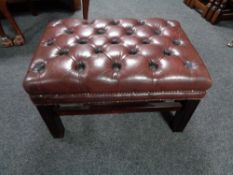 A red buttoned leather Chesterfield footstool on raised legs