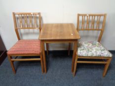 A pair of mid century teak dining chairs together with a teak occasional table