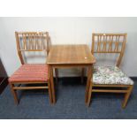 A pair of mid century teak dining chairs together with a teak occasional table