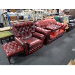 A red buttoned leather two seater settee together with similar armchair and two footstools