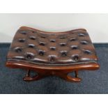 A brown buttoned leather upholstered footstool on X-frame support