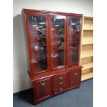 A triple door display cabinet in a mahogany finish