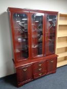 A triple door display cabinet in a mahogany finish