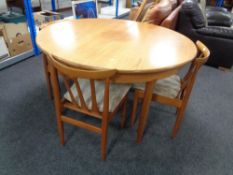 A circular teak G-plan extending dining table fitted a leaf together with three chairs