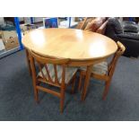 A circular teak G-plan extending dining table fitted a leaf together with three chairs