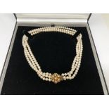 A triple strand cultured pearl necklace with gold clasp,
