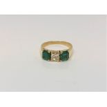 An 18ct gold emerald and diamond three stone ring, central diamond approximately 0.