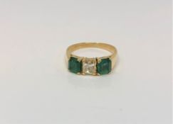 An 18ct gold emerald and diamond three stone ring, central diamond approximately 0.