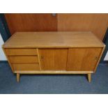 A mid century teak sliding door sideboard fitted with three drawers