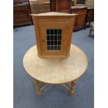 An oak leaded glass door corner cabinet together with circular blond oak coffee table