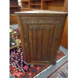 An oak linen fold hanging corner cabinet